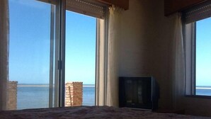 A room with a bed, a television, and a view of the sea through large windows. - Beautiful House Privileged Location Unique View (maldonado)