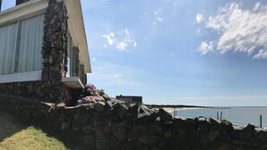 A coastal property with a stone wall, a white building with a balcony, and a view of the sea. - Beautiful House Privileged Location Unique View (maldonado)