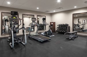 A gym with treadmills, elliptical machines, and weight benches.