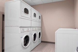 A laundry room with stacked washing machines and dryers.