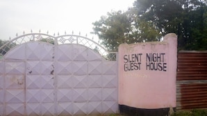 Uma entrada com portão e uma placa que diz "Silent Night Guest House" e um número de telefone.