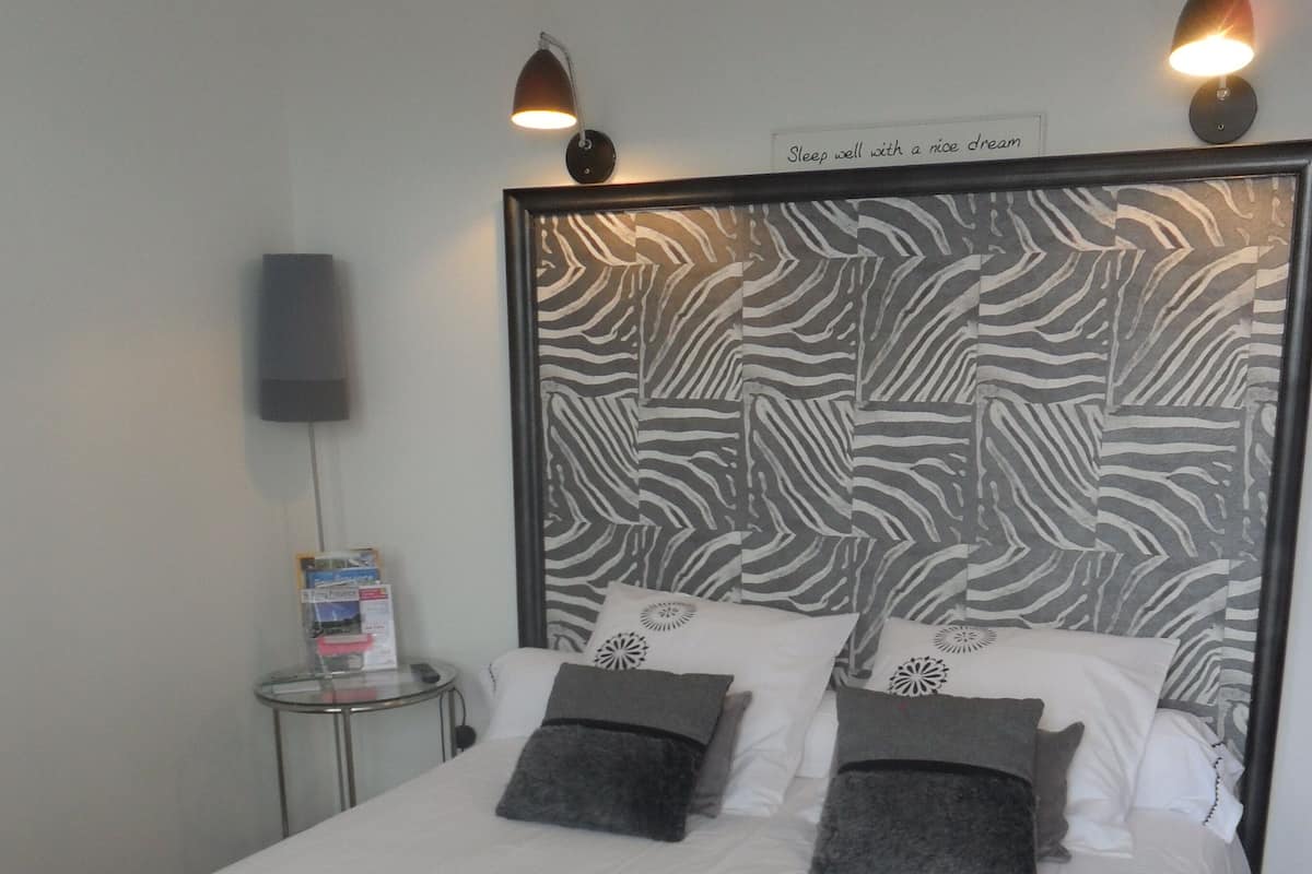 A neatly made bed with a zebra-patterned headboard, two bedside lamps, and a sign above the headboard that reads "Sleep well with a nice dream."