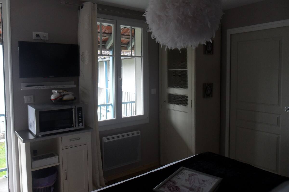 A compact kitchen with a microwave, a small refrigerator, and a window with a view of a balcony.