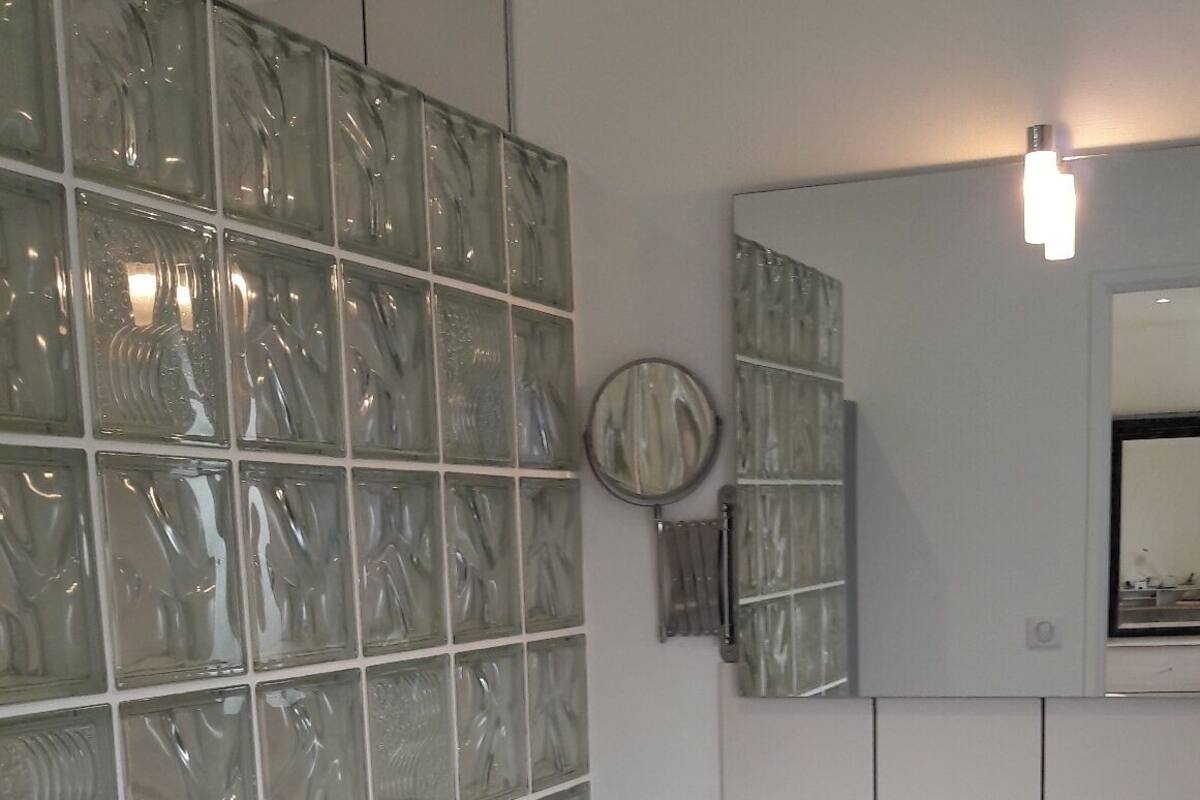 A bathroom with a white sink, grey cabinets, and a mirror above it.