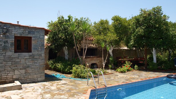 A stone building with a window, a swimming pool with a ladder, and surrounding greenery. - VILLA WITH  PRIVE POOLGARDEN AREA, bbq , wi-fi,  near sea , town, local tavern (rethymno)