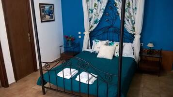 Een enkel bed met metalen frame, een nachtkastje, een lamp en een schilderij aan de muur.