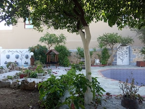 A garden with a wooden gazebo, potted plants, and a decorative wall. - VILLA WITH  PRIVE POOLGARDEN AREA, bbq , wi-fi,  near sea , town, local tavern (rethymno)