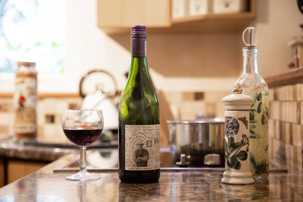 A bottle of wine, a glass of red wine, and a decorative container on a kitchen counter.