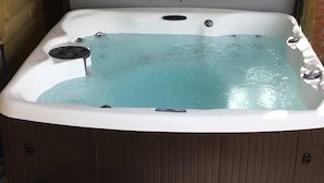 A hot tub with a control panel, a drain, and a wooden base. - Hop Cottage (Ashford)