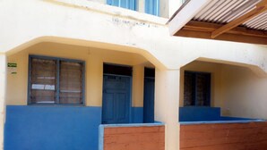 A building with a blue and white facade, a wooden bench, and a door labeled "ROOM 4". - The Place Bar And Restaurant (Oyugis)