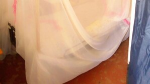 A room with a bed covered by a sheer white bedspread with pink trim. - The Place Bar And Restaurant (Oyugis)