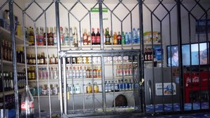 A bar area with a metal partition and shelves stocked with various beverages. - The Place Bar And Restaurant (Oyugis)
