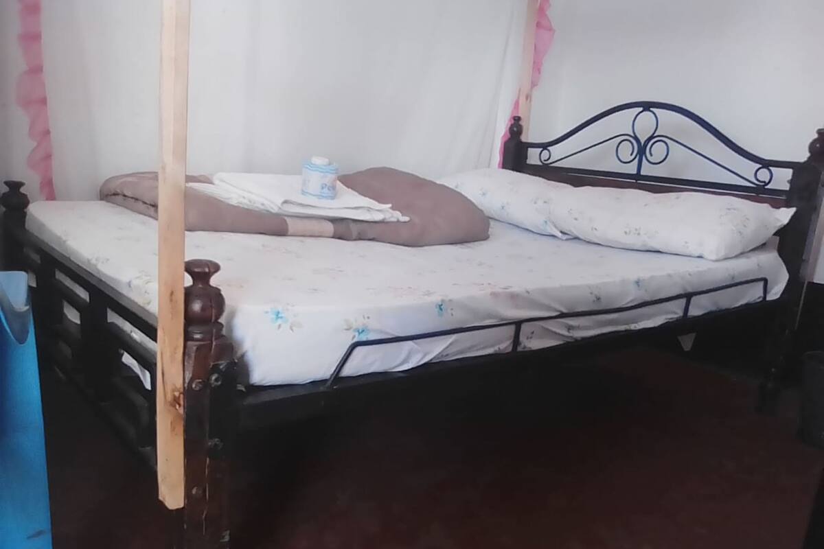 A single bed with a metal frame, a wooden headboard, and a floral-patterned bedspread.