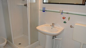 A bathroom with a shower, sink, toilet, and a glass shelf with decorative items. - Croce del Sud 39 - Lignano (Lignano Sabbiadoro)