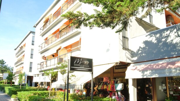 A multi-story building with balconies, a sign for 'M 50', and a shop with colorful bags. - Croce del Sud 39 - Lignano (Lignano Sabbiadoro)