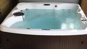 Un jacuzzi con panel de control, desagüe y base de madera.