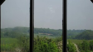 Vista a través de una ventana con paisaje rural, campos y árboles.