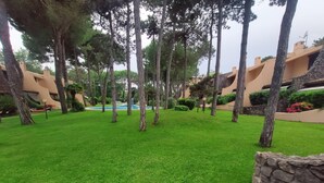 Ein gepflegter Innenhof mit Swimmingpool, umgeben von Bäumen und Gebäuden im mediterranen Stil.