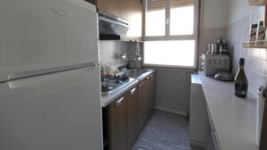 Una cocina compacta con refrigerador, estufa, lavaplatos y microondas.