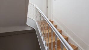 Una escalera con barandillas blancas y peldaños de madera que sube a un piso superior.