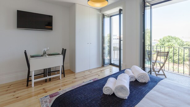 Un dormitorio moderno con cama, escritorio y balcón.