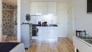 Una cocina compacta con armarios blancos, horno empotrado y un pequeño comedor con mesa y sillas.