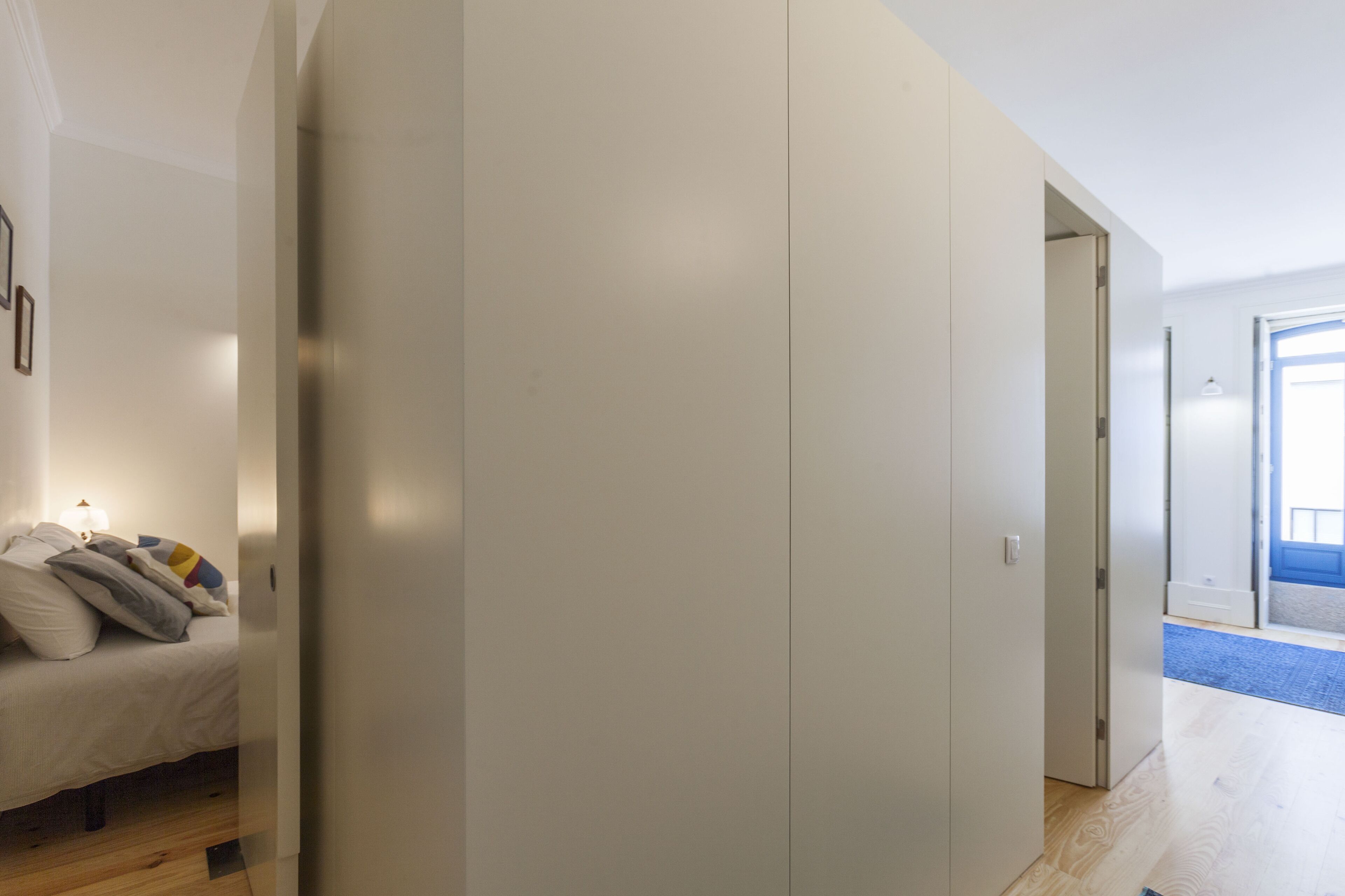 Un dormitorio con cama, armario y puerta que da a otra habitación.