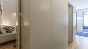 A bedroom with a bed, a wardrobe, and a door leading to another room.