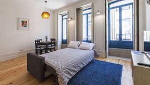 A bedroom with a bed, a desk, and a chair. There are two doors and a window.