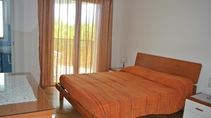 Een slaapkamer met een houten bed, een nachtkastje en een raam met gordijnen.