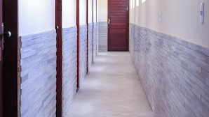 A long, narrow hallway with a tiled floor and walls, leading to a wooden door at the end. - Pousada Meu Xodó (São Miguel dos Milagres)