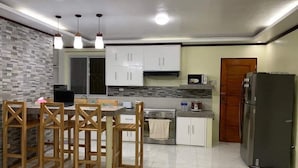 Une cuisine moderne dotée d’un îlot central, de meubles blancs, d’un four à micro-ondes, d’une cuisinière et d’un réfrigérateur.