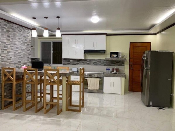 A modern kitchen with a central island, white cabinets, a microwave, a stove, and a refrigerator.