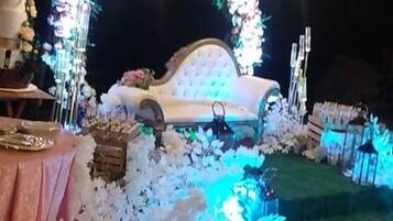 Decoració de boda a l'aire lliure, amb una arcada floral, un sofà blanc i una zona de menjador.