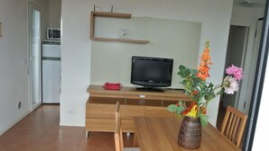 Une cuisine moderne avec une table en bois, des chaises, un téléviseur et un vase rempli de fleurs.