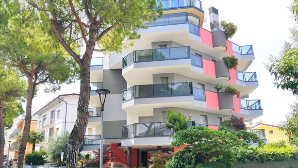 Un immeuble résidentiel à plusieurs étages, doté de balcons, d’une entrée sécurisée et entouré de verdure.