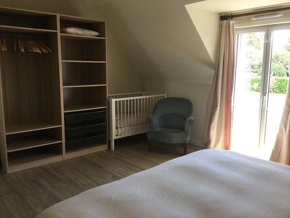 Un dormitorio con un armario grande, una cuna, una silla y una cama.