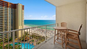 A balcony with a view of a beach and a swimming pool.