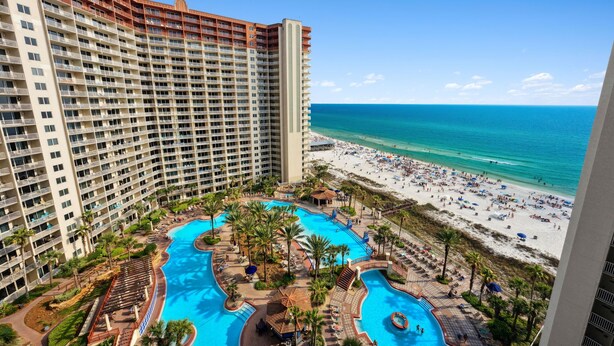 A high-rise hotel with a large pool area and a beach view.