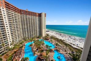 A high-rise hotel with a large pool area and a beach view.