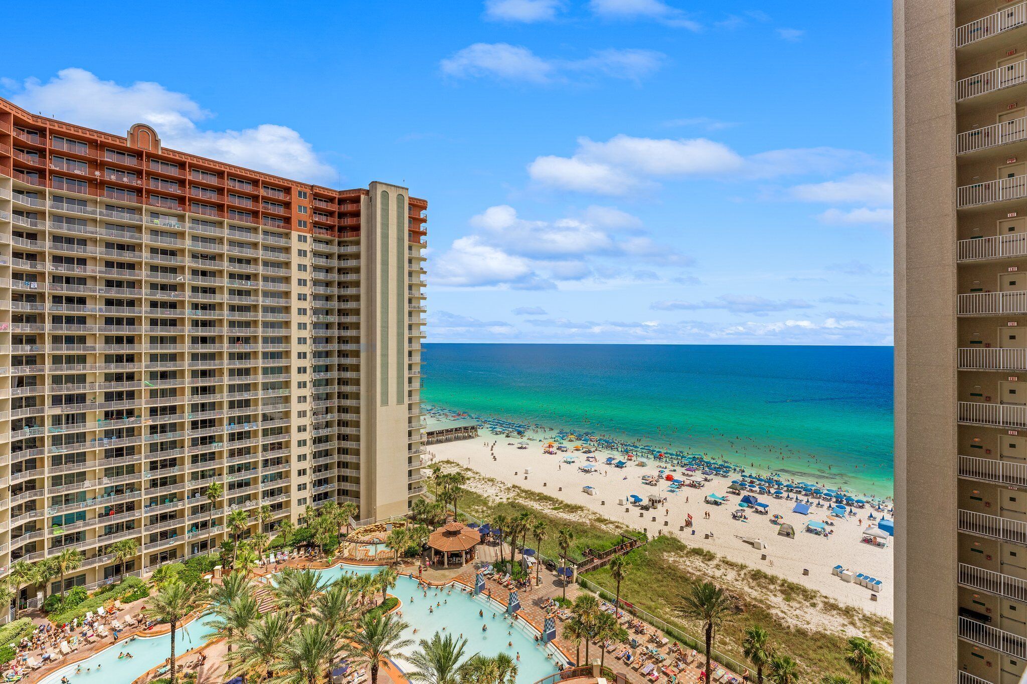 A high-rise hotel with a beach view, a pool area, and multiple balconies.