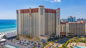 A high-rise hotel with multiple floors, a central tower, and a beach view.