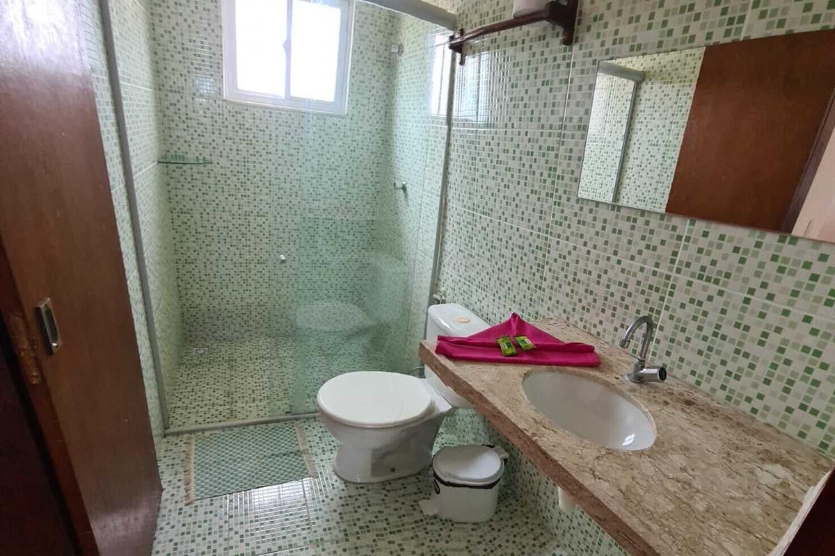 A bathroom with a shower, toilet, sink, and a mirror.