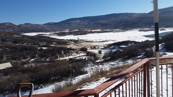 Un paisaje nevado con vistas despejadas a un valle, un edificio pequeño y montañas distantes.