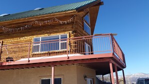 Een houten chalet met een balkon, grote ramen en een metalen hekwerk.
