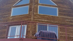 Een houten huis met twee verdiepingen, een balkon en een auto ervoor geparkeerd.