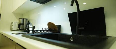 A modern kitchen with a black sink, stainless steel appliances, and a sleek countertop.