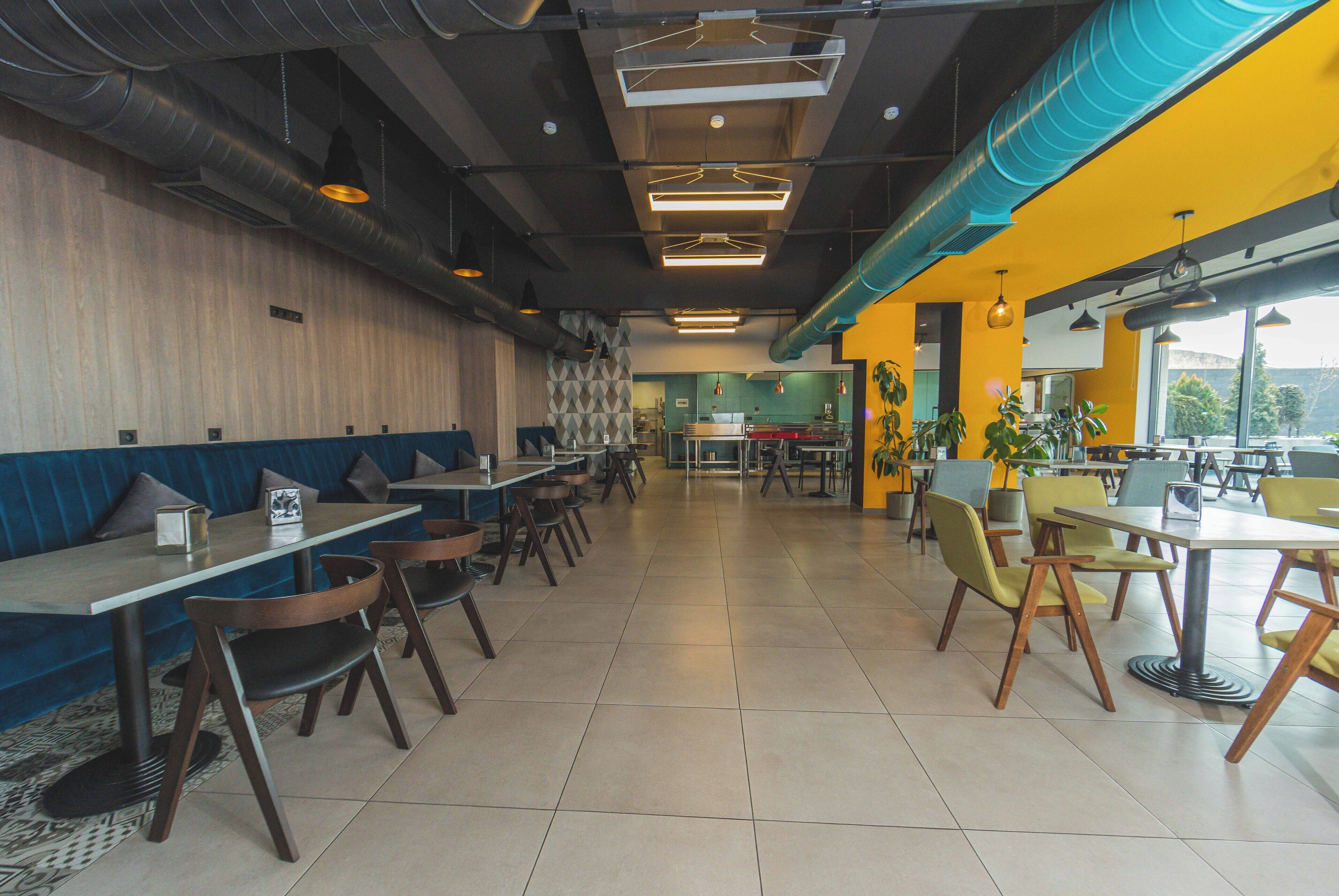 A spacious restaurant with high ceilings, exposed ductwork, and a mix of booth and table seating.