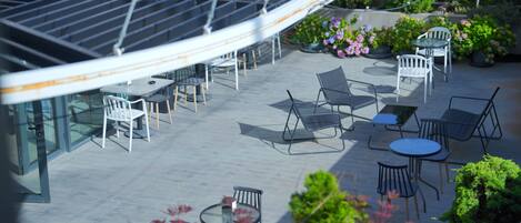 Una terrazza sul tetto con posti a sedere all'aperto e una struttura in vetro.
