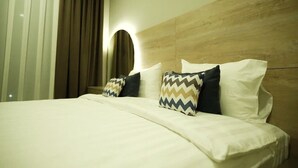Een hotelkamer met een bed, een hoofdeinde met ingebouwde verlichting en een raam met gordijnen.